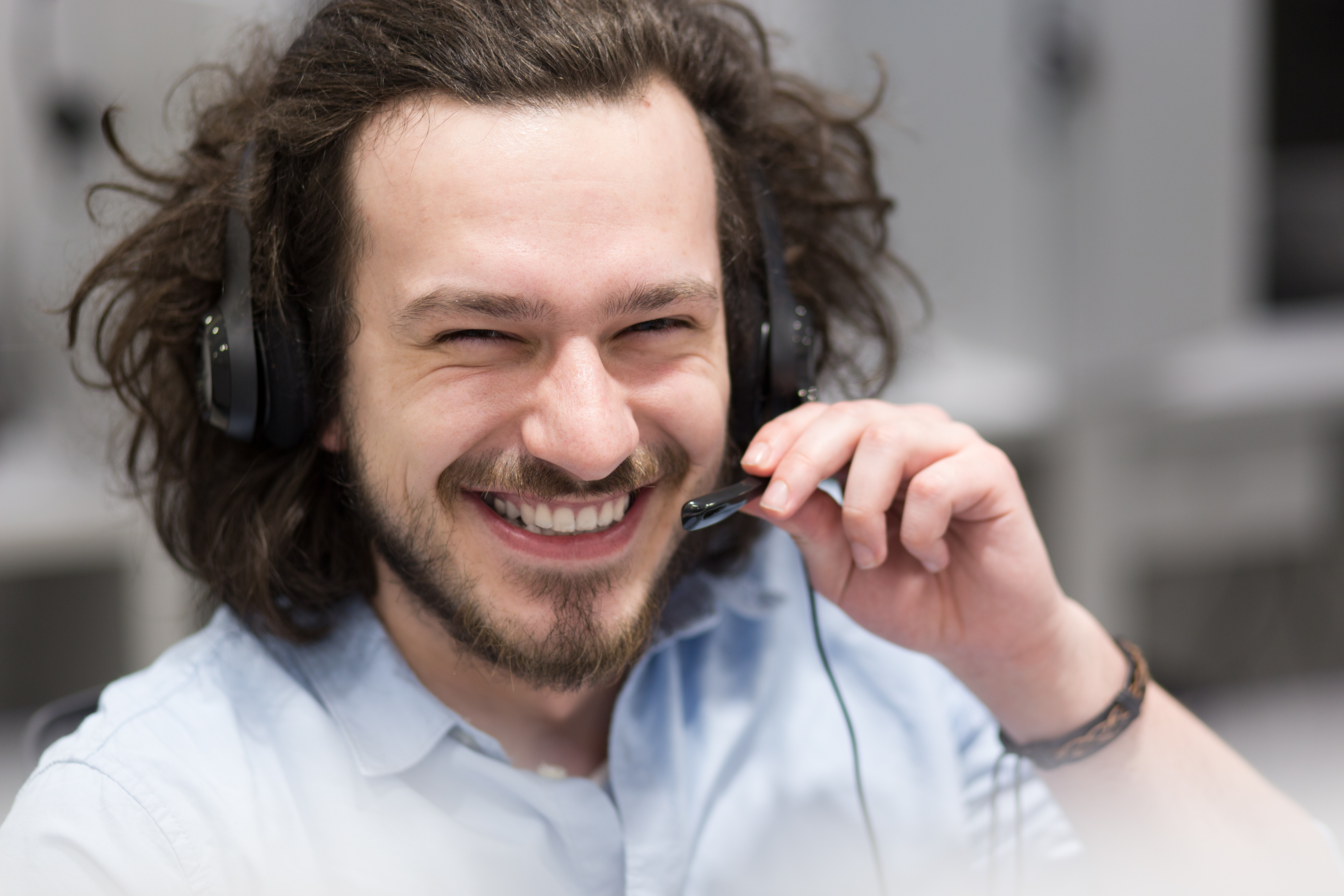 young male smiling while on the phone doing his job with a headset